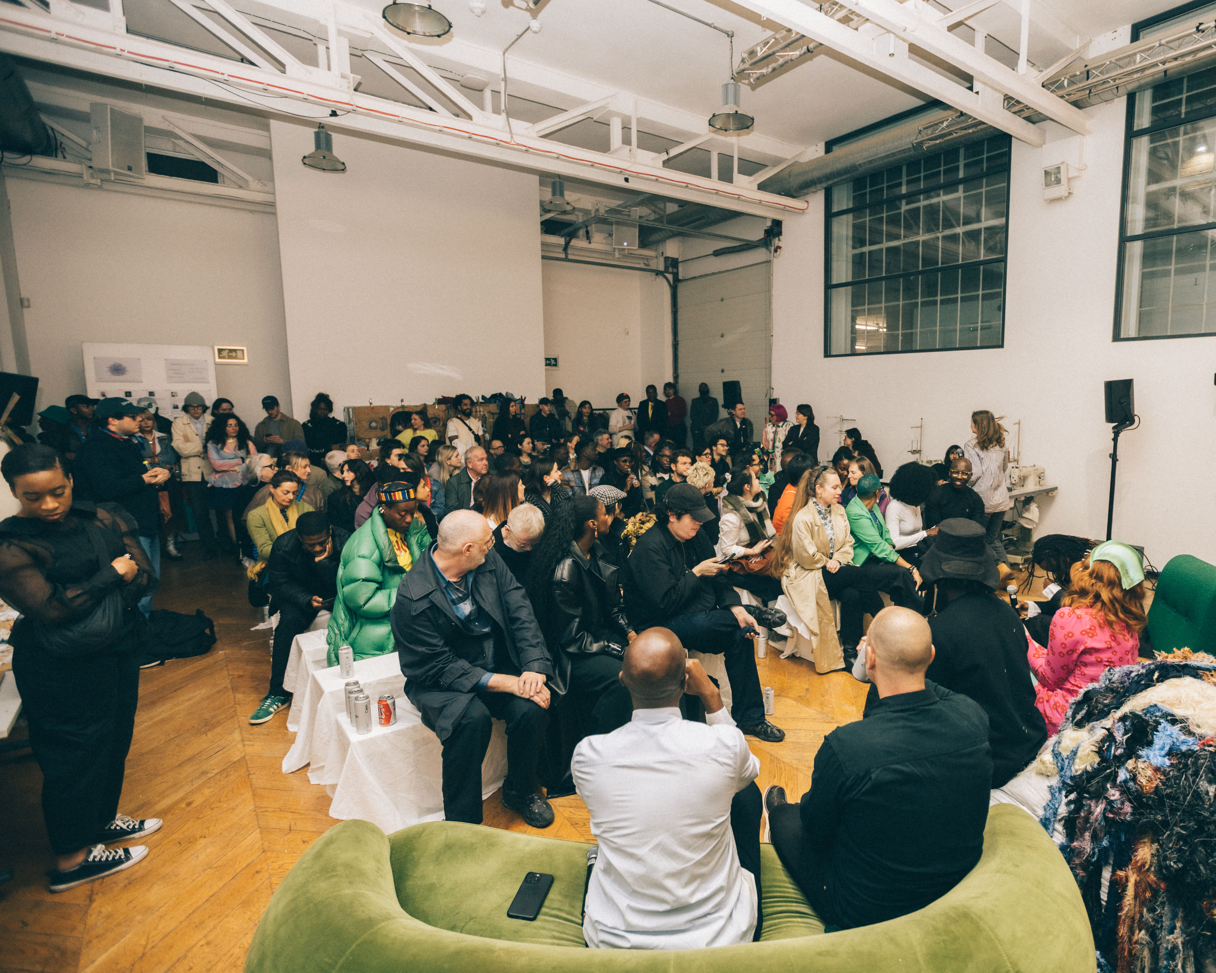 A group of atleast 30 people seated before a panel of seated speakers
