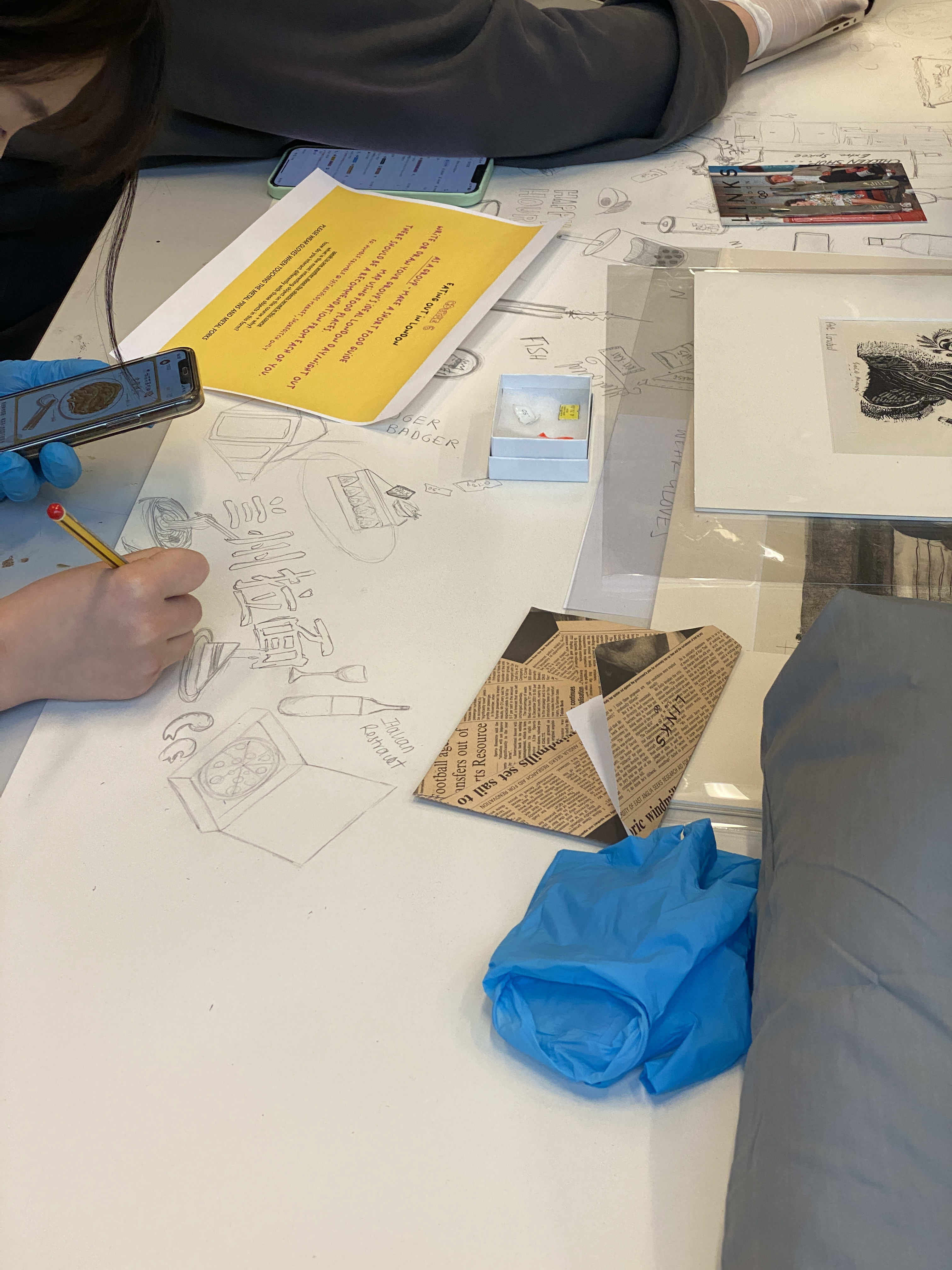 Materials on a table with people's hands just visible