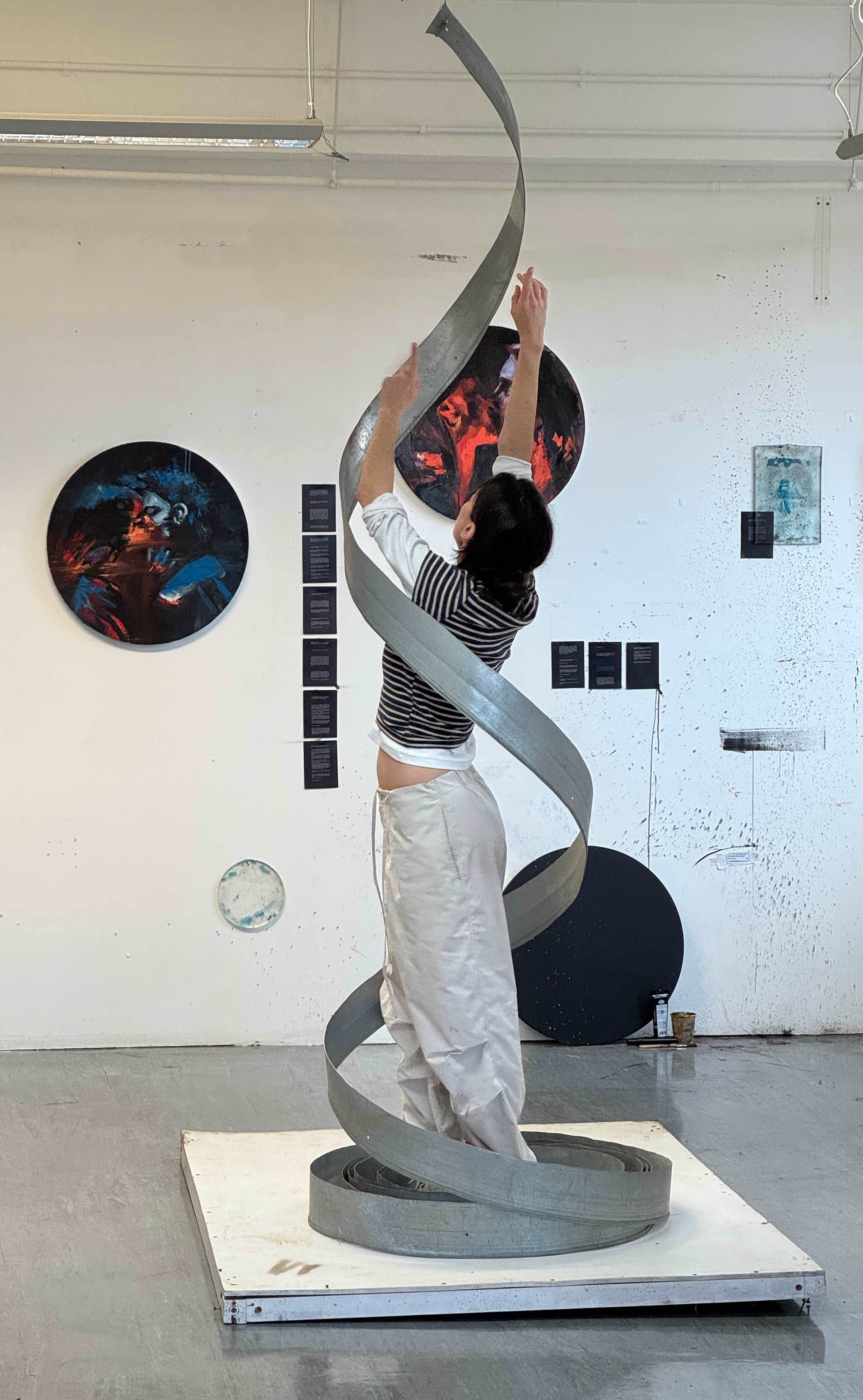 An image of a person standing inside the curve of a large steel installation