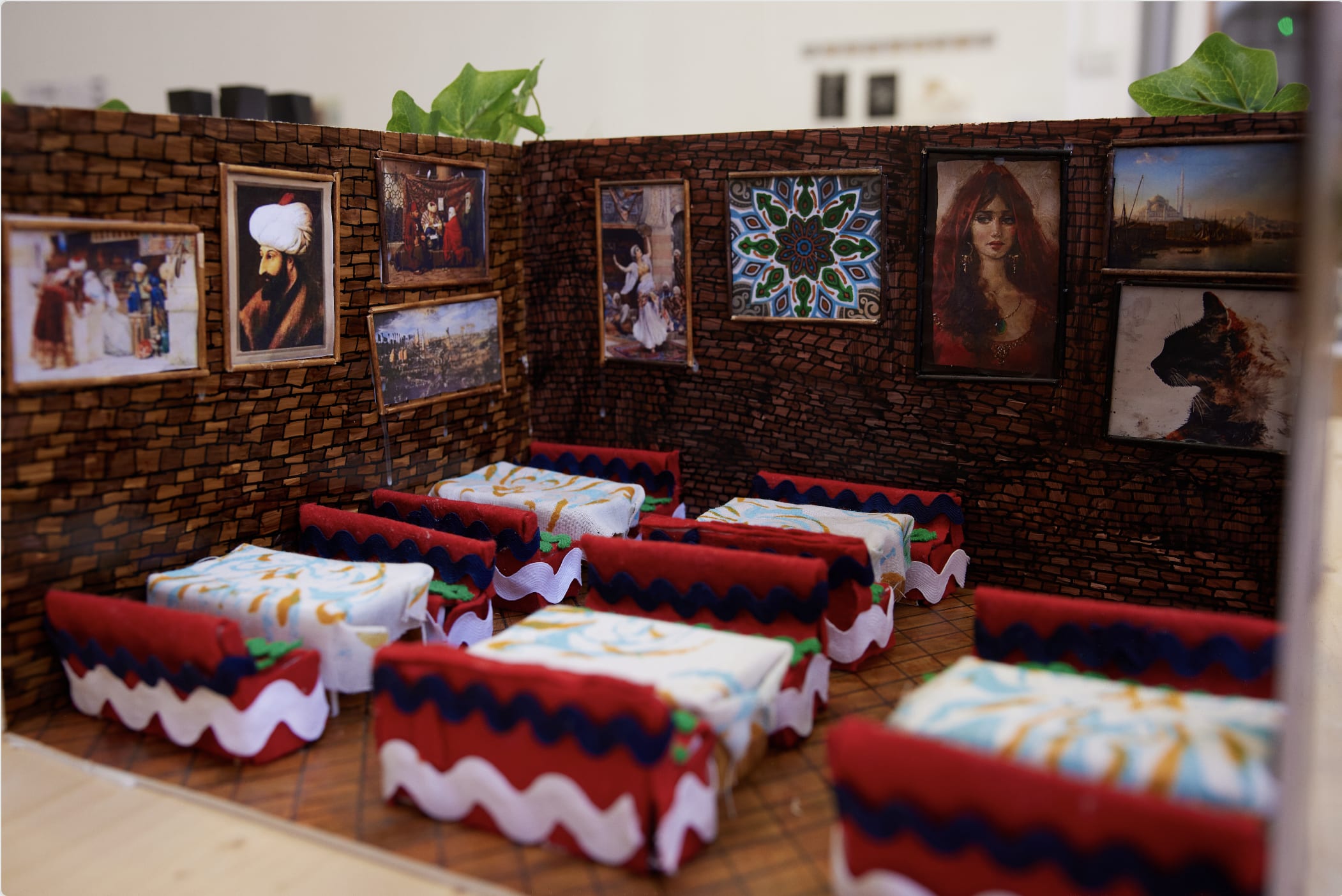 A small model depicting a traditional Arabic coffeeshop with brick wall and framed portraits and mosaics