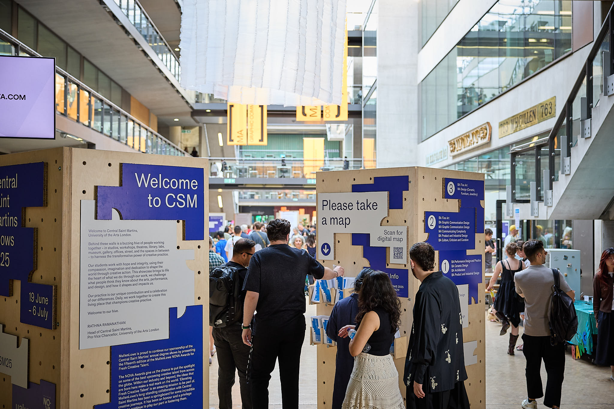 A group of people wandering around the CSM street during the CSM shows 2025. There are blue and white posters and imagery stating 'Welcome to CSM'