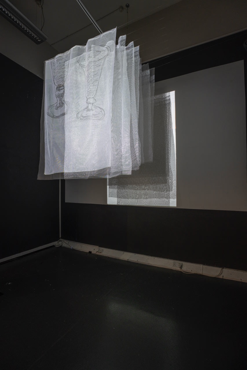 Hanging white squares of material with films projected over the top. 