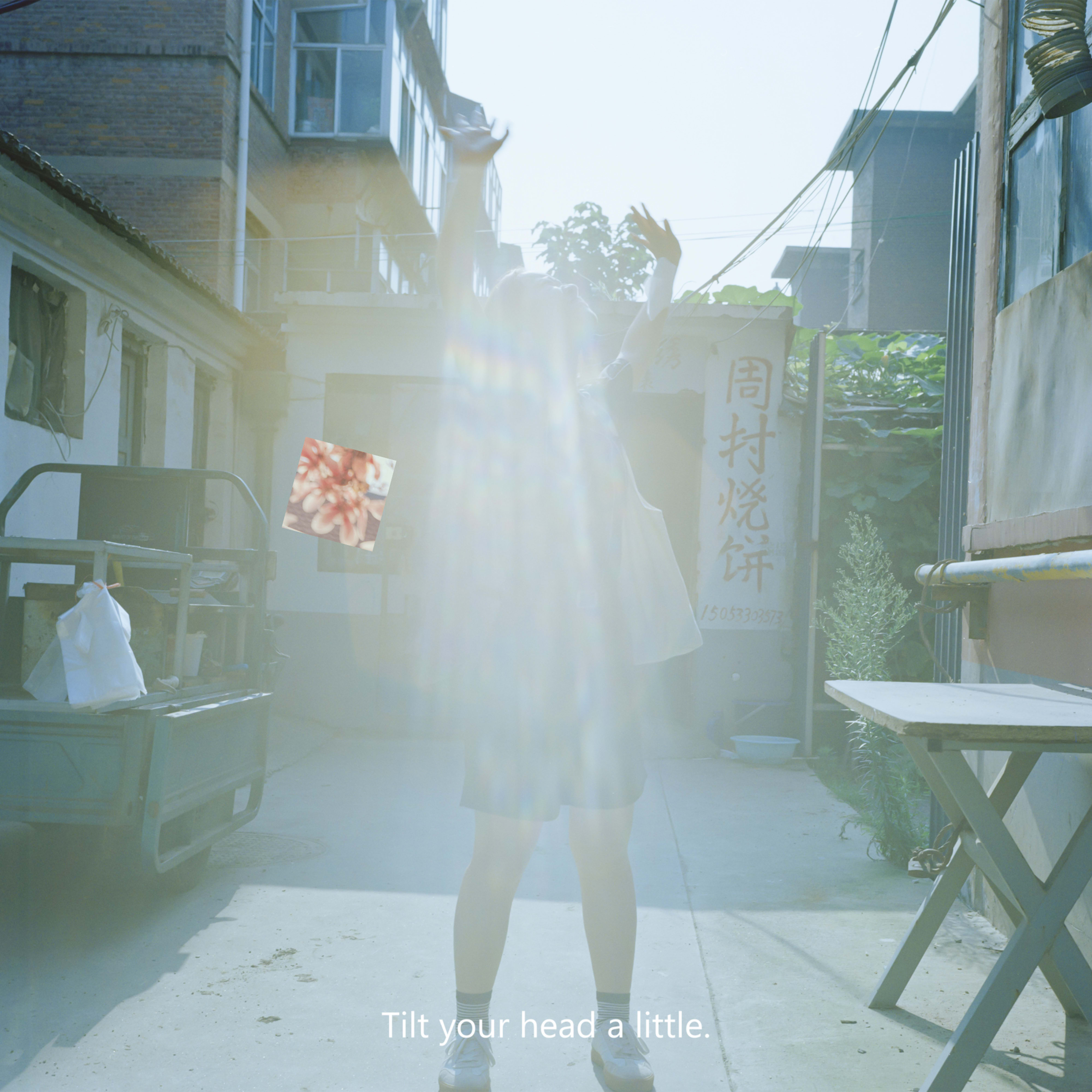 Photograph of a figure standing in the middle of a sunny street.