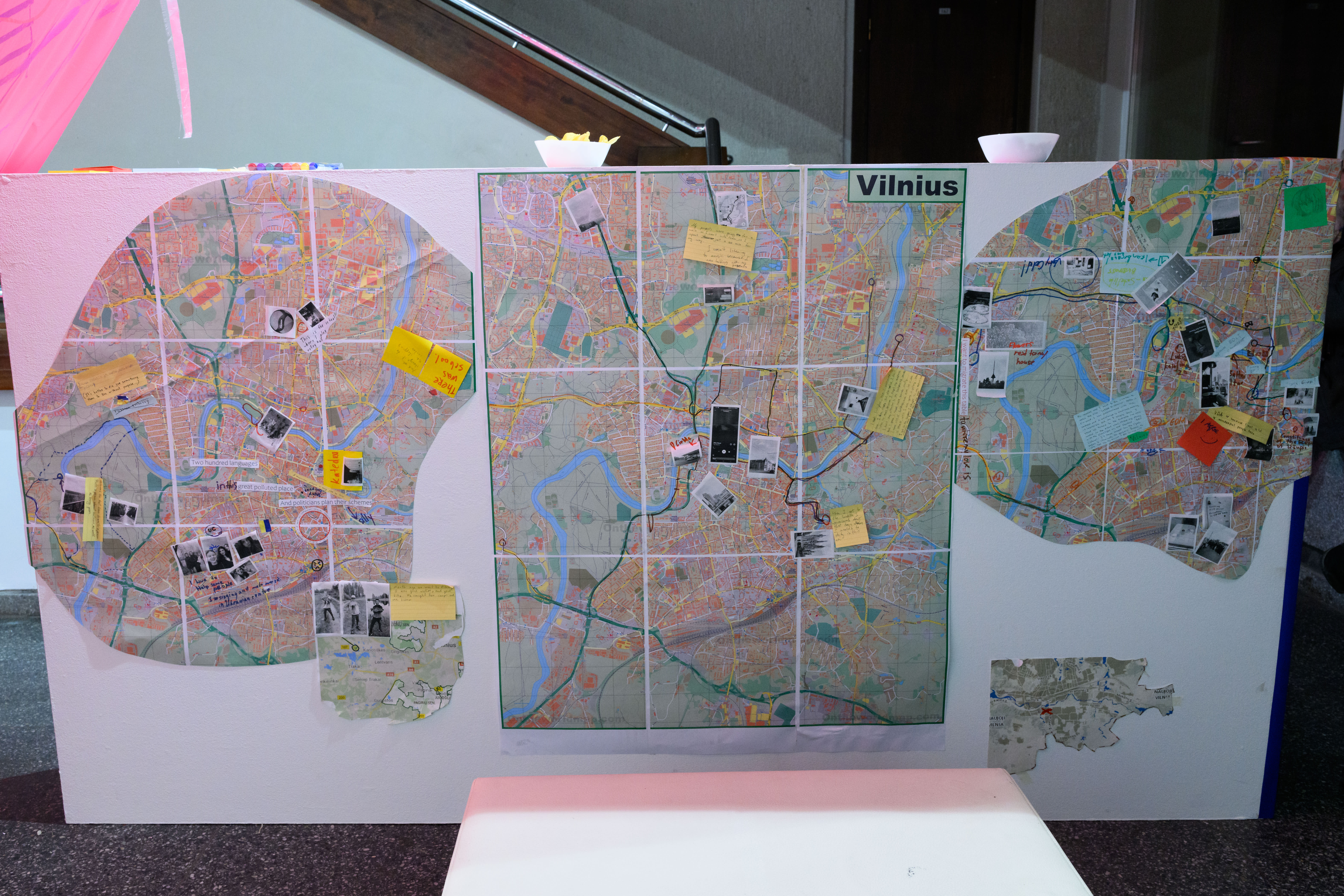 A map of Vilnius across 3 different shapes on a white board. The map is plotted with people's notes and pins 