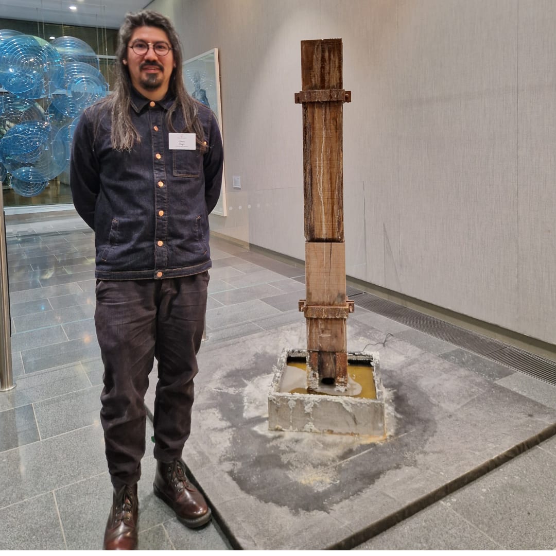 An image of a man standing infront of a work of art