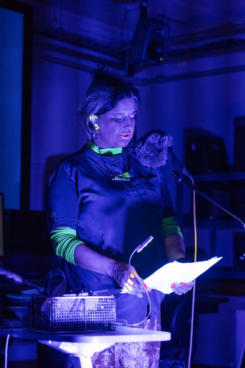 A performer at an exhibition, light by an intense blue light. 