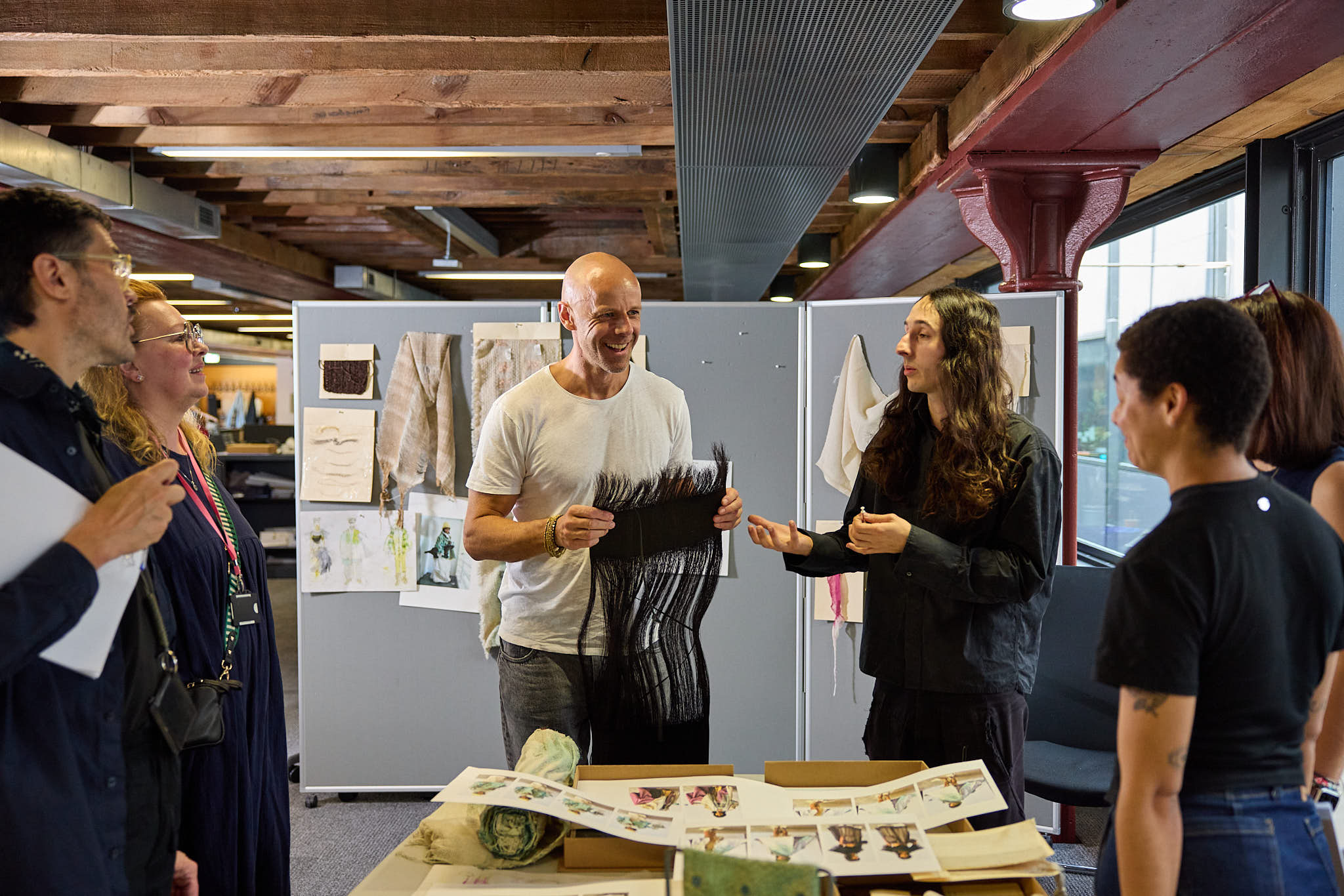 An image of several people hurdled around a table inspecting woven materials