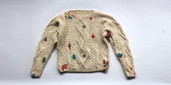 A beige/white woolen jumper with colourful splodges all over