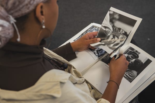 A photo taken from behind of a young woman working at a desk and creating a collage