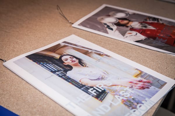 Fashion magazines attached to a cork board.