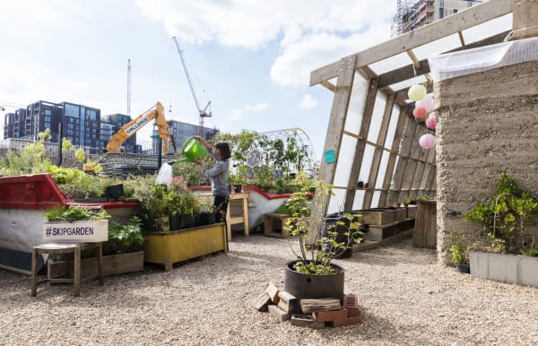 City rooftop garden with planters and a person watering plants