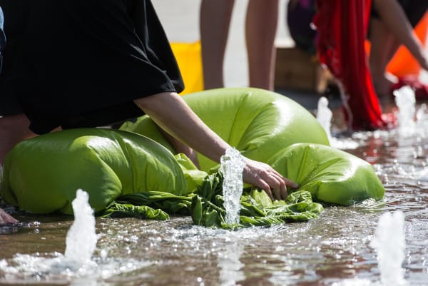 Hands working green fabric in water of fountain