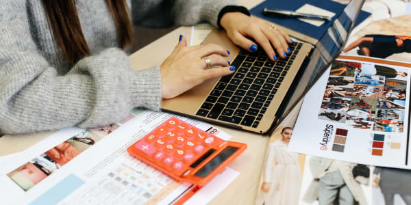 Student in the studio, working on laptop and calculator