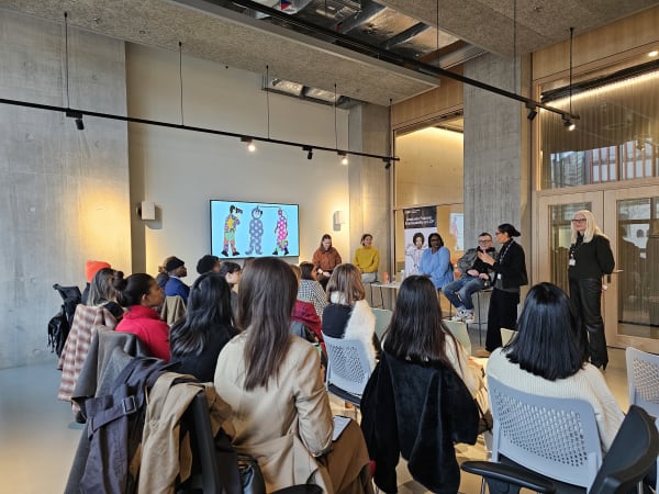 A panel of 4 guest speakers and 2 staff members introducing the event in front of an audience. 