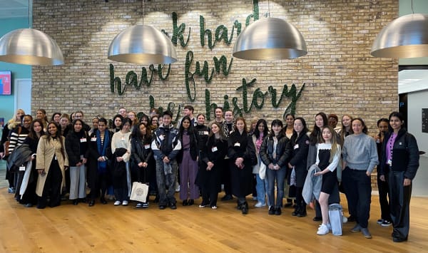 A group of students standing in front of a grey wall at Amazon HQ
