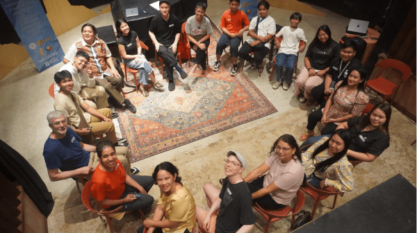 a group of people sitting in a circle, smiling to the camera