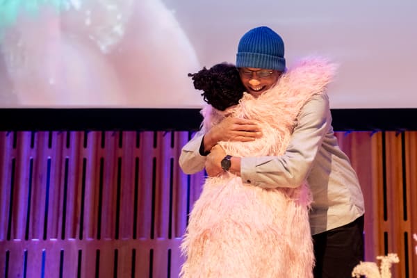 A woman hugging a man on stage at an wards ceremony