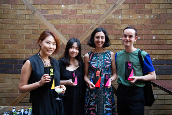Four people standing in a row holding awards