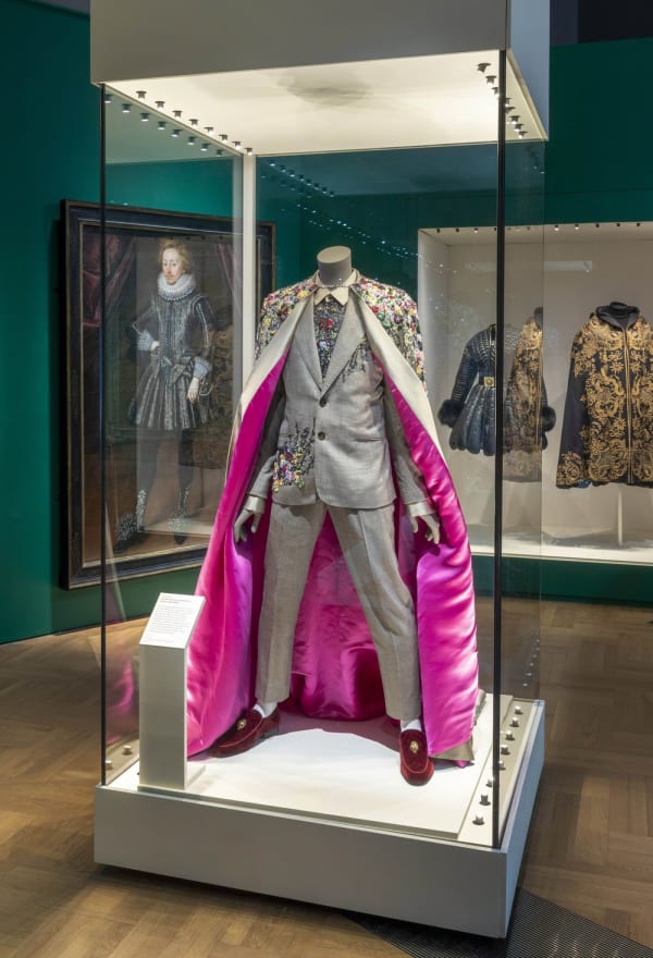 mannequin wearing men's attire of suit and pink lined cloak