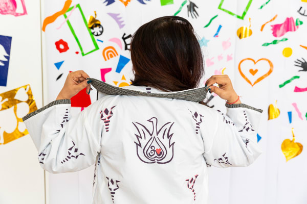 Person wearing white jacket with colourful embroidery