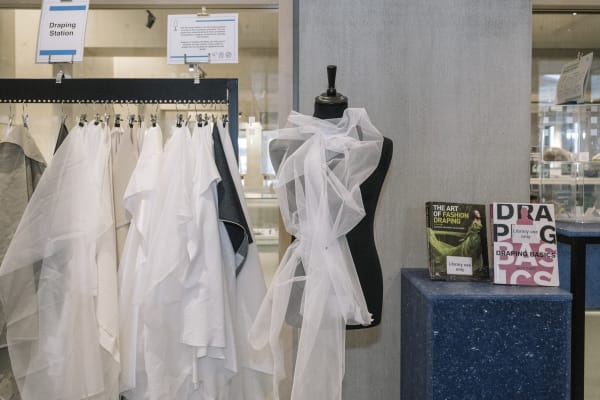 Mannequin in white lace, rack with white sheets hung up.