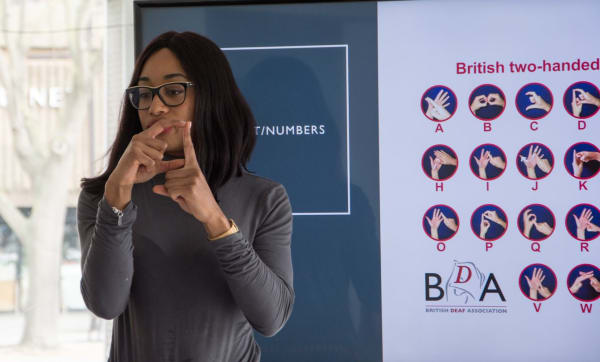 Sharifa Edwards signing a letter in British Sign Language during a workshop