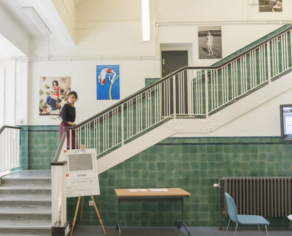 A student walks up the stairs at UAL's Lime Grove site. The walls are tiled green.