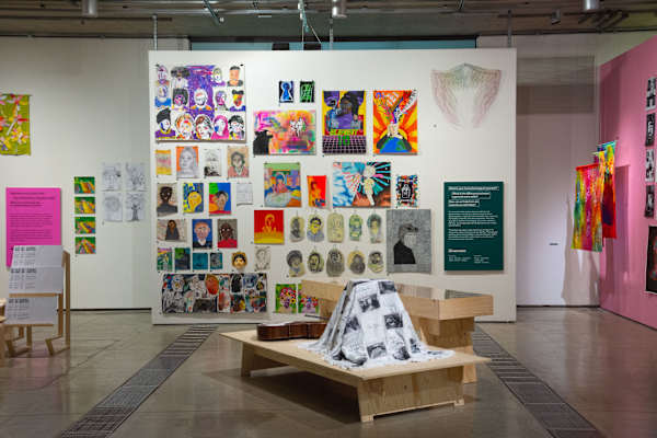 Gallery space with many brightly coloured pictures on the walls