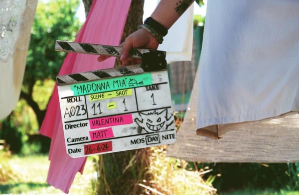 A person holding a clapper board with 'Madonna Mia' written on it