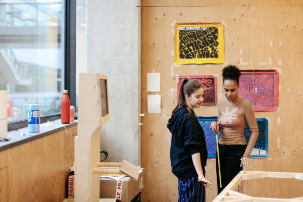 Two people working arranging work on wall