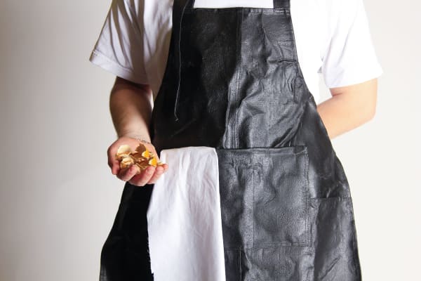 Close up chest view of man wearing Ben Apron with right hand holding up dried fruit skins
