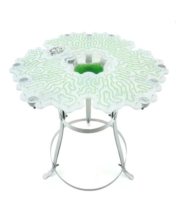 A table with green circuit board made of algae and metal legs