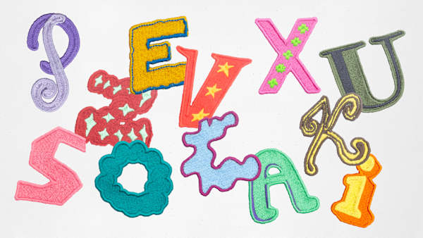 Colourful embroidered letterforms arranged randomly on a light background, showcasing the bespoke LGBTQ+ History Month alphabet.