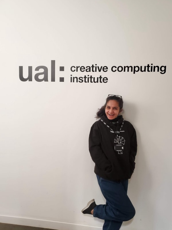Student standing in front of UAL logo