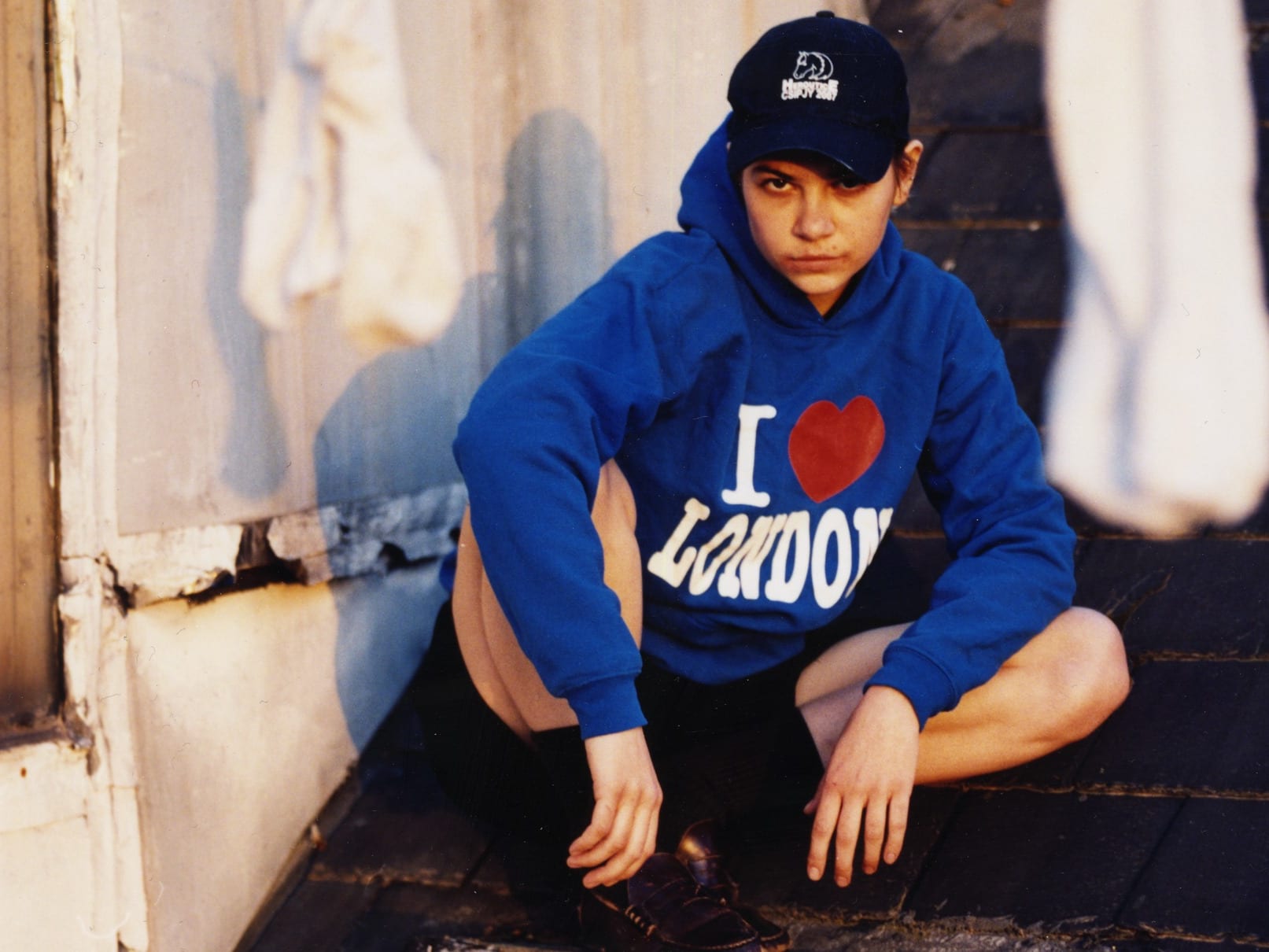 A girl squatting in a 'I Love London' hoodie