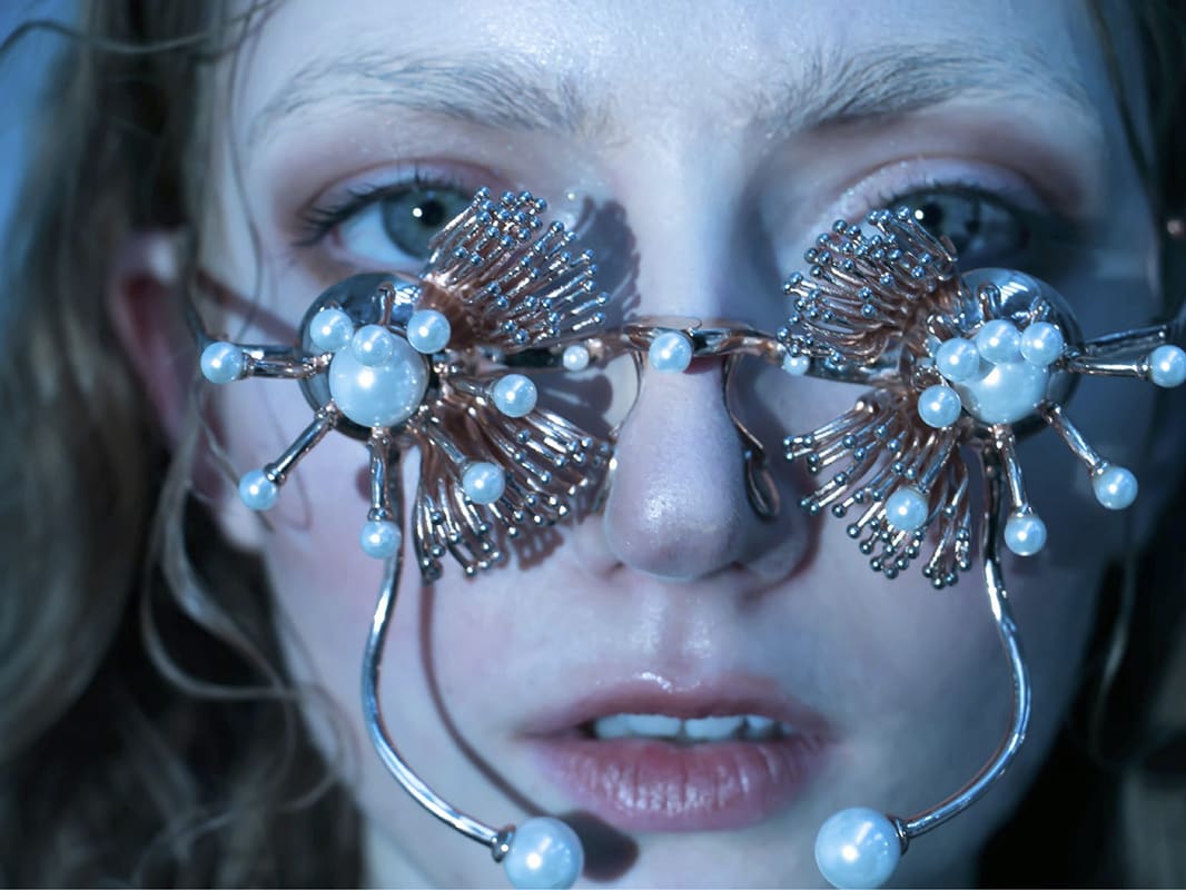 Female model wearing pearl and gold embellished glasses.