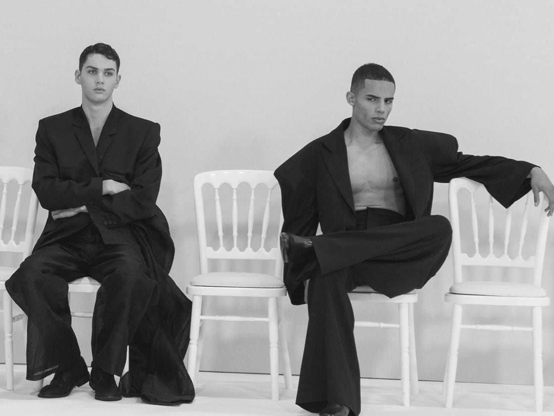 Four male models seated in loose black clothing