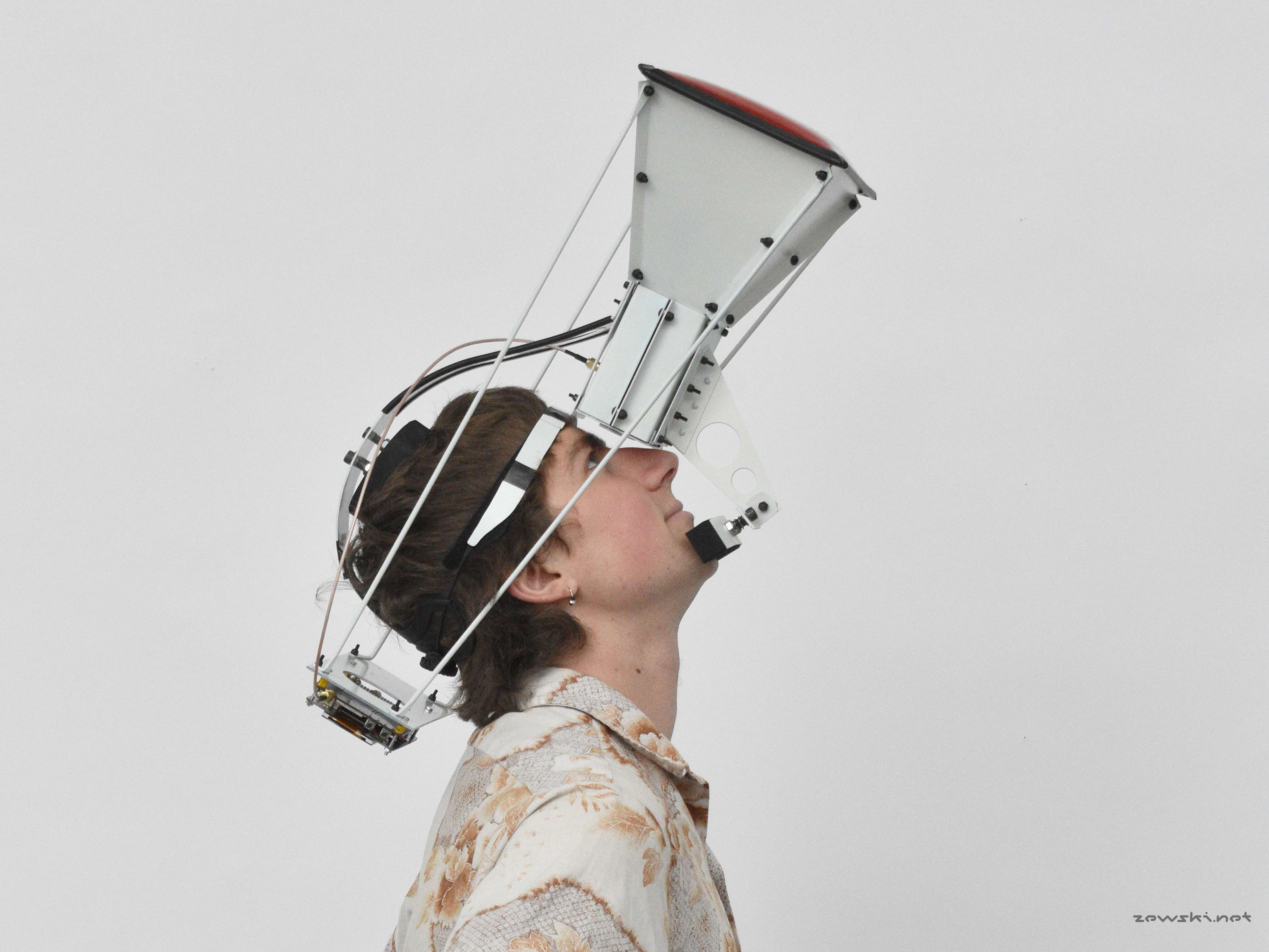 Young adult white male looks upwards into a metal construction strapped to his head