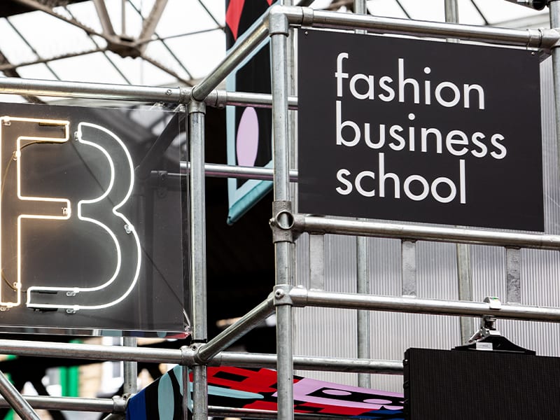 Zoomed into a letter B constructed on scaffolding with a sign that reads Fashion Business School