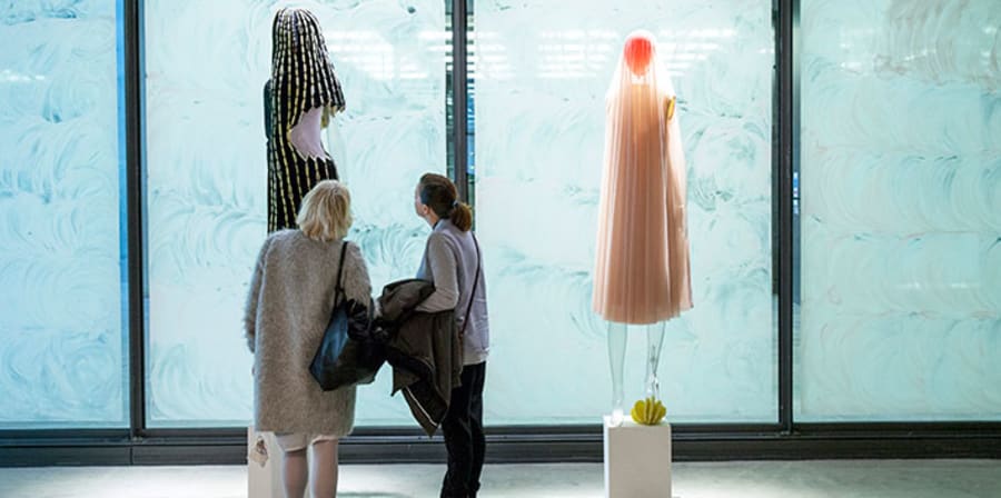 Two people looking at garments on mannequins 