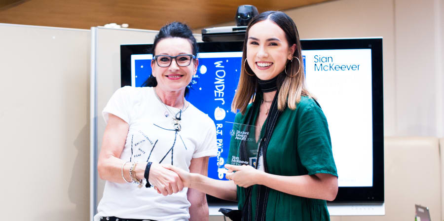 Illustration student Sian McKeever stands with award for student design for Penguin Random House