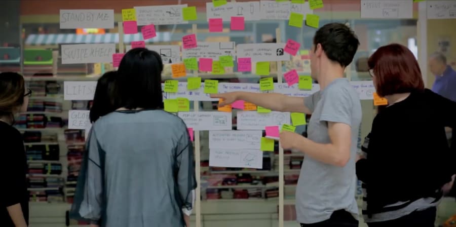 Four people in front of a wall full of sticky notes.