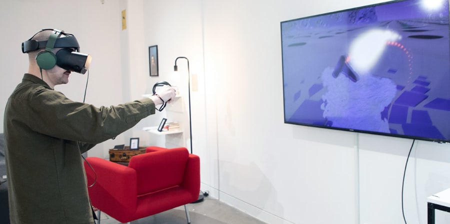 An audience member uses a VR headset to play Fractus.