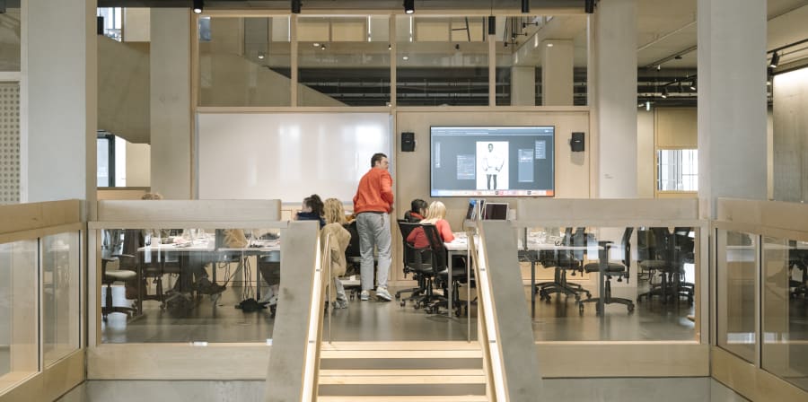 Someone standing up showing people slides in an open space with tables and chairs