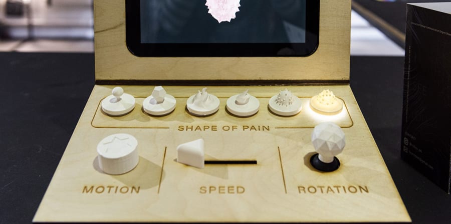 Student Ruizheng Lyu's project, a wooden computer featuring different objects denoting pain scales.