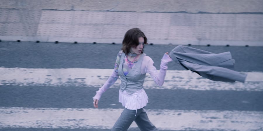 person walking across zebra crossing flinging jacket over shoulder