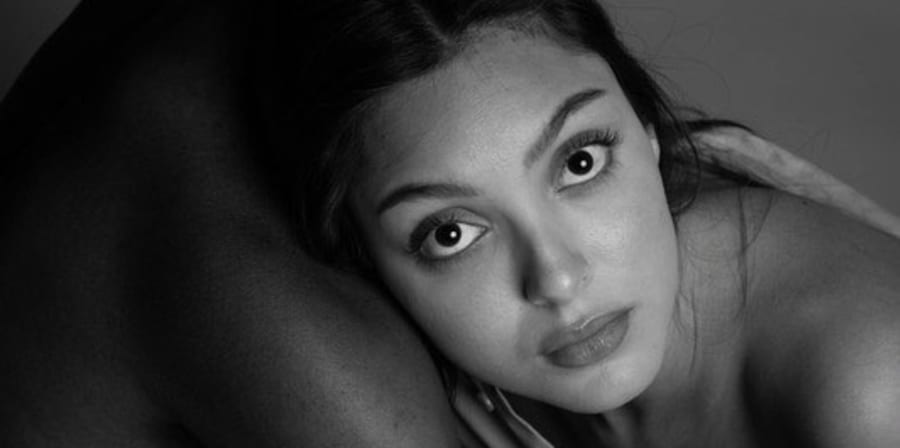 A black and white photographs of a model leaning on another model's chest.
