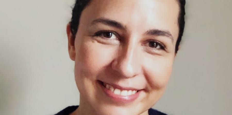 Close up of a smiling woman with hair tied back and a black jumper