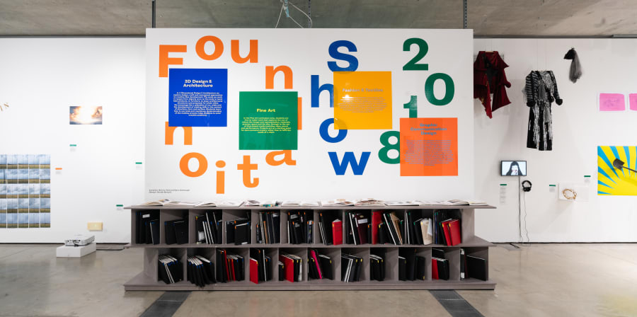 Work on display in a gallery, Foundation Show 2018 is written on the wall is bold green, orange and blue letters