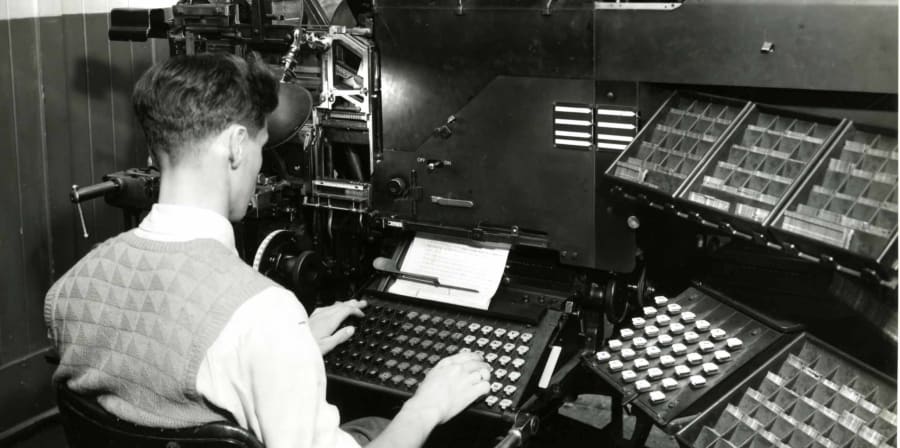 Black-and-white photograph of person working at letterpress machine